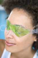 Woman sitting poolside using eye mask