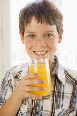 Young boy indoors drinking orange juice smiling