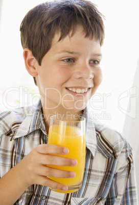 Young boy indoors drinking orange juice smiling