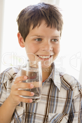 Young boy indoors drinking water smiling