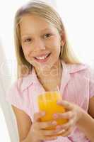 Young girl indoors drinking orange juice smiling