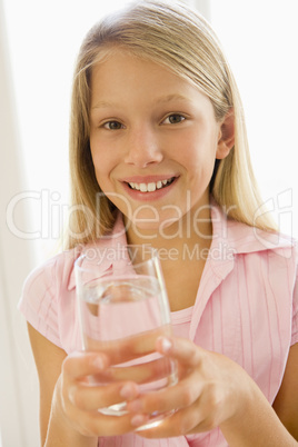 Young girl indoors drinking water smiling