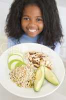 Young girl in kitchen eating rice fruit and nuts smiling