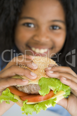 Young girl eating cheeseburger smiling
