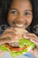 Young girl eating cheeseburger smiling