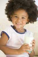 Young girl indoors drinking milk smiling