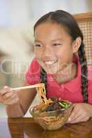 Young girl in dining room eating chinese food smiling