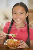 Young girl in dining room eating chinese food smiling