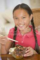 Young girl in dining room eating chinese food smiling