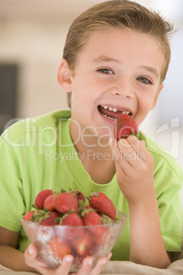 Young boy eating strawberries in living room smiling