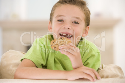 Young boy eating cookie in living room smiling