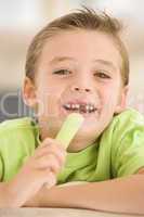 Young boy eating celery in living room smiling