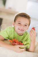 Young boy eating bowl of vegetables in living room smiling