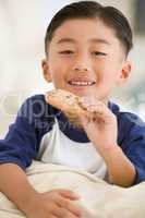 Young boy eating cookie in living room smiling