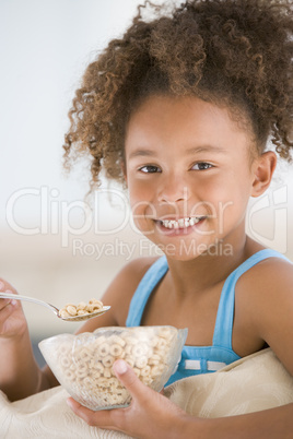 Young girl eating cereal in living room smiling