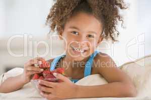Young girl eating strawberries in living room smiling