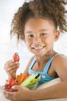 Young girl eating bowl of vegetables in living room smiling