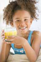 Young girl drinking orange juice in living room smiling