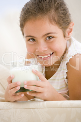 Young girl drinking milk in living room smiling