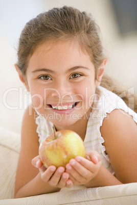 Young girl eating apple in living room smiling