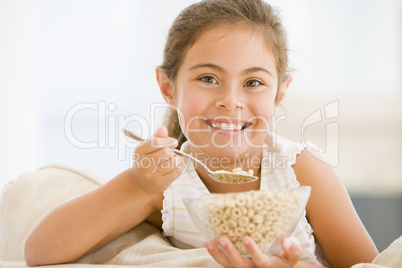 Young girl eating cereal in living room smiling