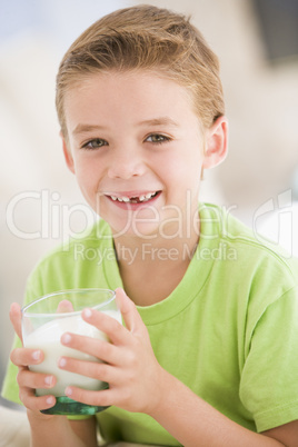 Young boy indoors drinking milk smiling