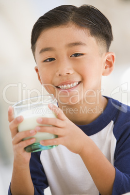 Young boy indoors drinking milk smiling
