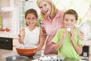 Woman and two children in kitchen baking and smiling