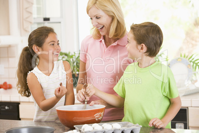 Woman and two children in kitchen baking and smiling