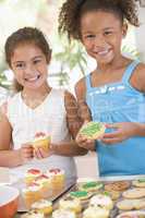 Two children in kitchen decorating cookies smiling