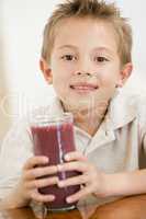 Young boy indoors drinking juice smiling