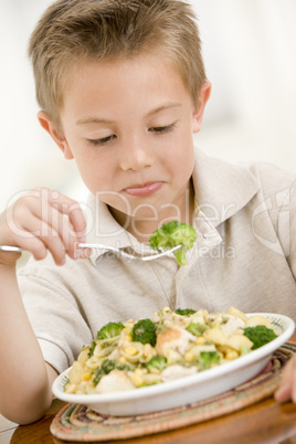 Young boy indoors eating pasta with brocolli
