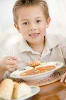 Young boy indoors eating soup