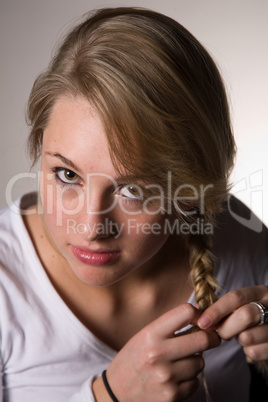 junge blonde Frau flechtet sich Zopf