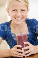 Young girl indoors drinking juice smiling