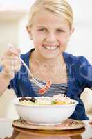 Young girl indoors eating seafood smiling