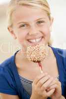 Young girl indoors eating candy apple smiling