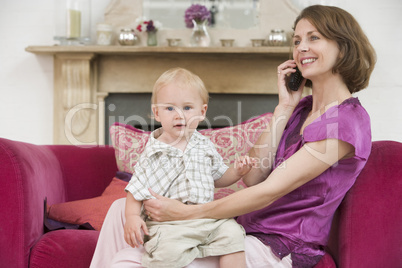 Mother using telephone in living room with baby smiling