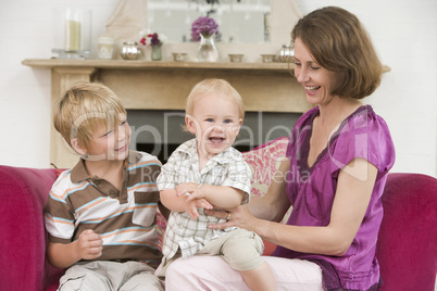 Mother in living room with baby and young boy smiling