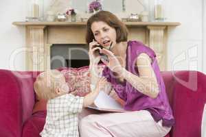 Mother using telephone in living room with baby frowning