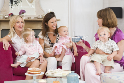 Three mothers in living room with babies and coffee smiling