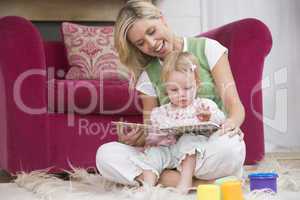 Mother in living room reading book with baby smiling