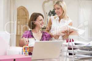 Two women and a baby in home office with laptop
