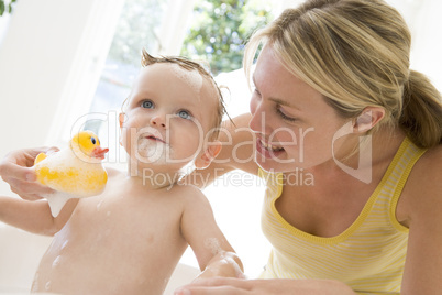 Mother giving baby bubble bath smiling