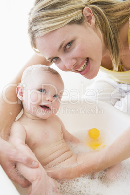 Mother giving baby bubble bath smiling