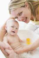 Mother giving baby bubble bath smiling