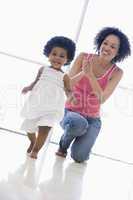 Mother and daughter indoors playing and smiling