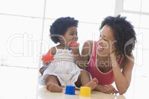 Mother and daughter indoors playing and smiling