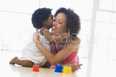 Mother and daughter indoors kissing and smiling