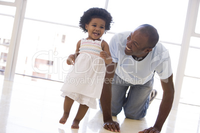 Father and daughter indoors playing and smiling